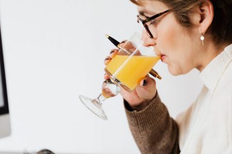 Nutrition Careers - Focused female drinking refreshing juice while working at table in office