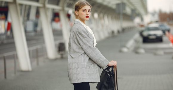 Tourism Careers - Stylish young woman with suitcase near car parking in airport