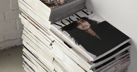 Publishing Internship - High angle many fashion magazines stacked on floor against white brick wall in studio