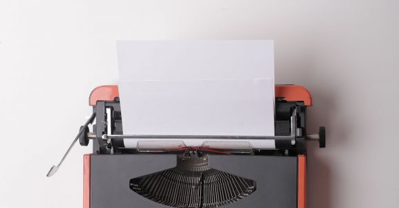 Journalism Careers - From above crop person using vintage black and red typewriter with white blank sheet of paper against white background